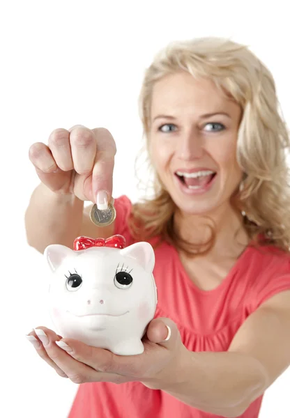 Mujer sonriente poniendo moneda de dinero en Piggybank — Foto de Stock