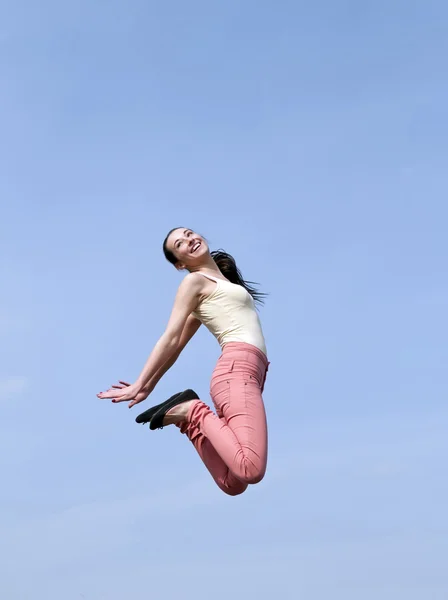 Donna che salta nel cielo blu — Foto Stock