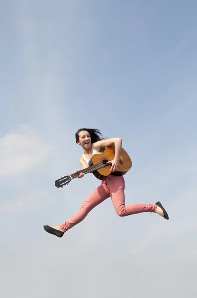 Mujer saltando con la guitarra en el cielo azul — Foto de Stock