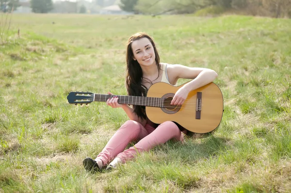 Mujer tocando la guitarra en un prado — Foto de Stock
