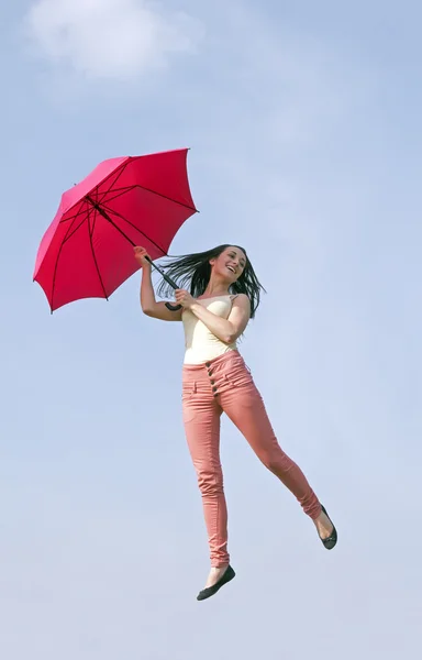 Vrouw springen met paraplu in blauwe hemel — Stockfoto