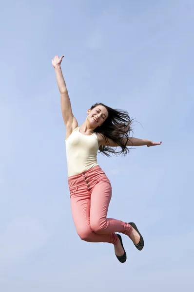 Mujer saltando al cielo azul Imagen de archivo