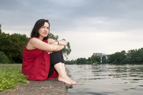 Giovane donna seduta sul fiume — Foto Stock