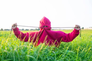 Çayırda oturan kapüşonlu genç kız.