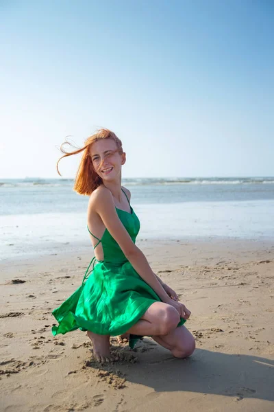 ビーチの緑のドレスを着た幸せな若い女の子 — ストック写真