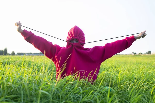 フードを着た少女が牧草地に座り — ストック写真