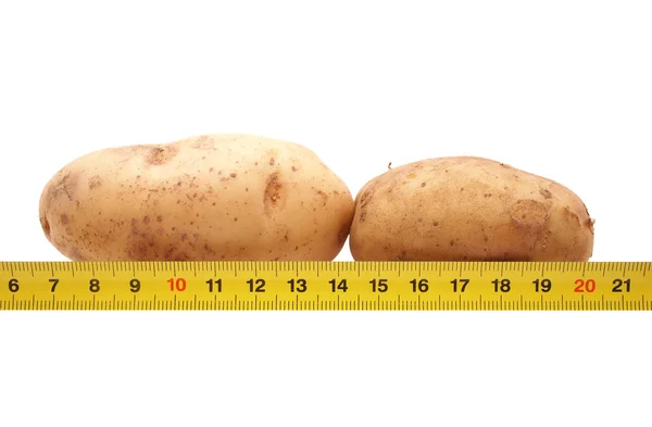 Patatas y una regla sobre un fondo blanco —  Fotos de Stock