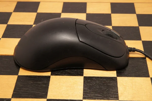 Computer mouse on a black chess board — Stock Photo, Image