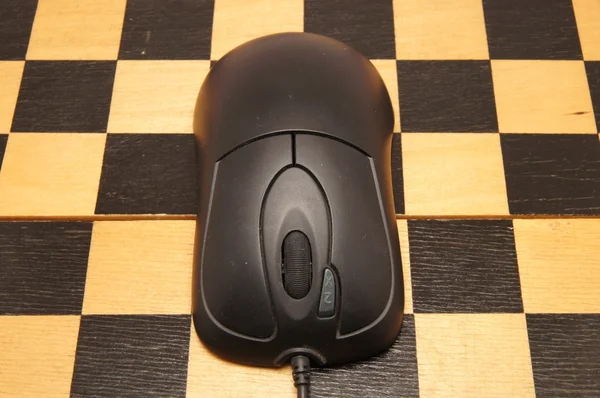 Ratón de ordenador en un tablero de ajedrez negro —  Fotos de Stock
