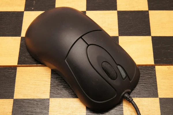 Computer mouse on a black chess board — Stock Photo, Image