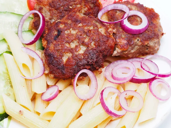 Schnitzels met groenten en pasta op een witte achtergrond — Stockfoto