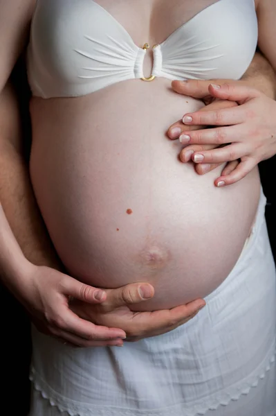 Bras autour du ventre de la femme enceinte — Photo