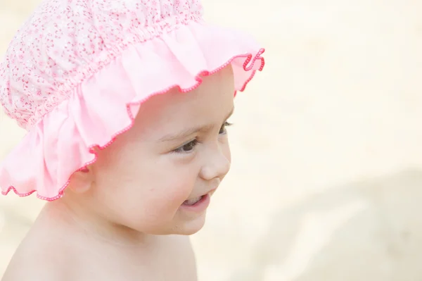 Ritratto di una bambina sorridente con un cofano rosa primo piano — Foto Stock