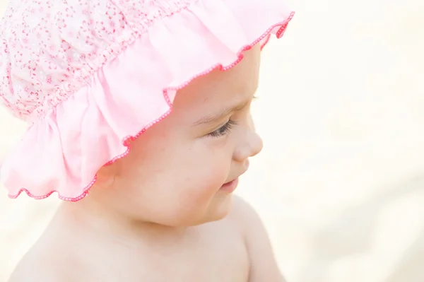 Ritratto di una bambina sorridente con un cofano rosa primo piano — Foto Stock