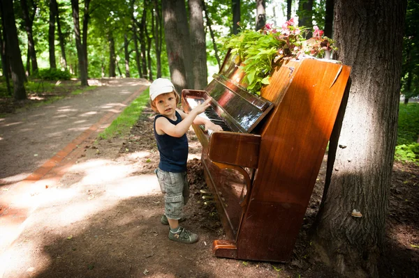 El niño está tocando el piano en el parque — Foto de Stock