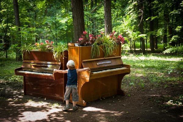 El niño está tocando dos pianos en el parque. — Foto de Stock