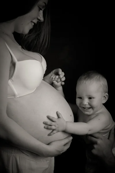 Uma criança toca a barriga de uma mulher grávida — Fotografia de Stock