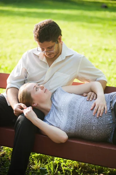 Těhotná žena se svým manželem v parku — Stock fotografie