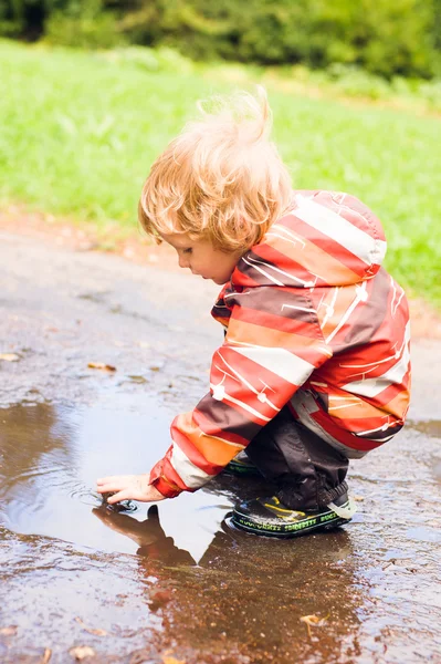 一个男孩在一个水坑中扮演 — 图库照片