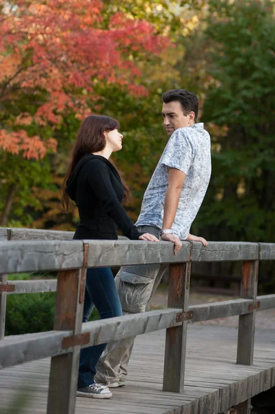 Zamilovaný pár na mostě v parku — Stock fotografie