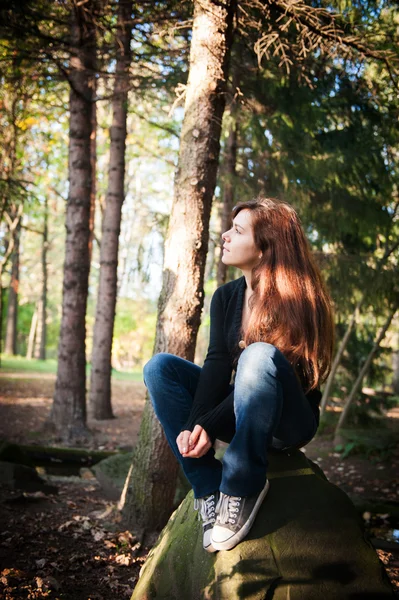 Belle fille assise sur un rocher dans la forêt — Photo