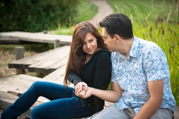 Pareja enamorada sentada en el puente en el parque de otoño — Foto de Stock