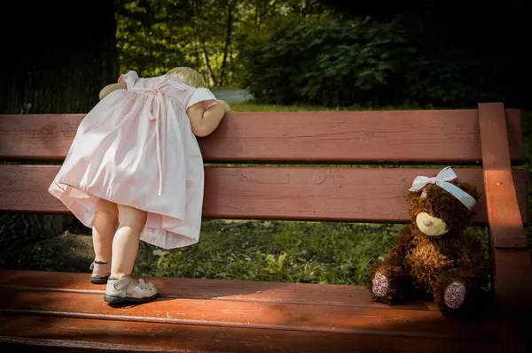 küçük kız bir oyuncak ayı ile tezgah sırtını dönüyor