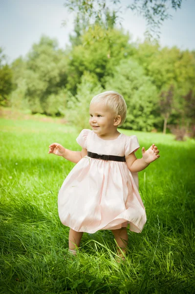 Menina bonito de pé na grama e sorrindo — Fotografia de Stock