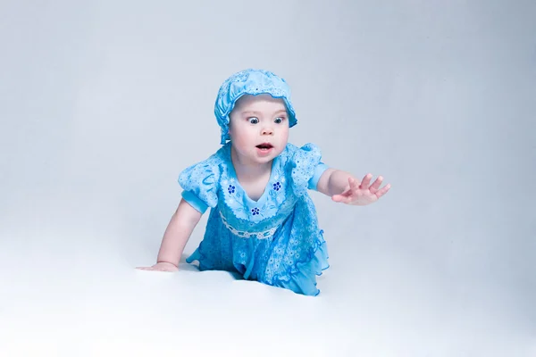 Niedliches kleines Mädchen in blauem Kleid und Hut kriecht — Stockfoto