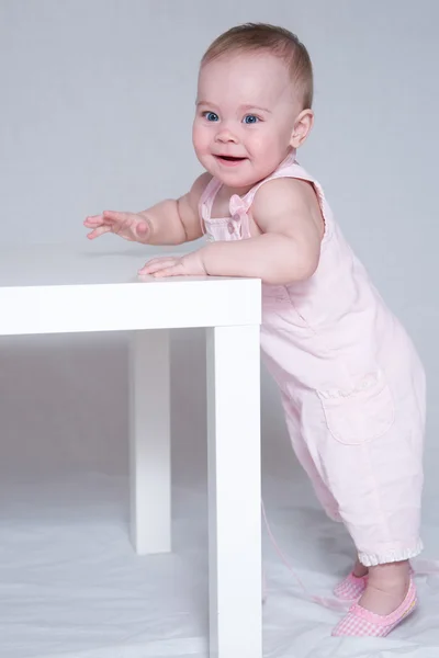 sevimli küçük kız ayakta, bir masanın üzerine eğilerek