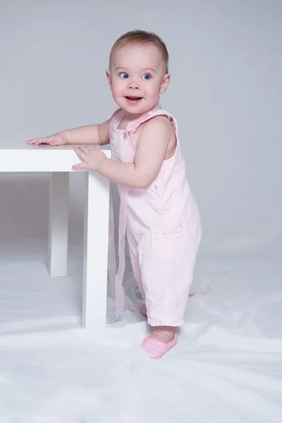 Linda niña de pie, apoyada en una mesa — Foto de Stock