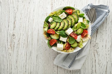 Sağlıklı yeşil salata, avokado ve ahşap masada beyaz peynir.