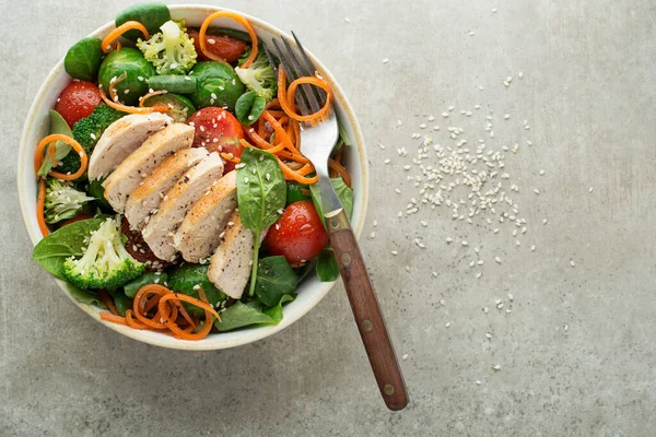 Healthy green salad with chicken breast and cooked vegetables on grey background. Healthy meal