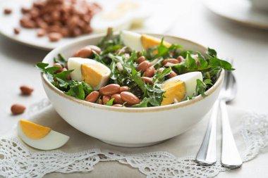 Healthy dandelion salad with beans and egg on white background close up clipart