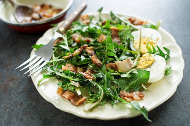 Dandelion salad with eggs and roasted bacon close up clipart