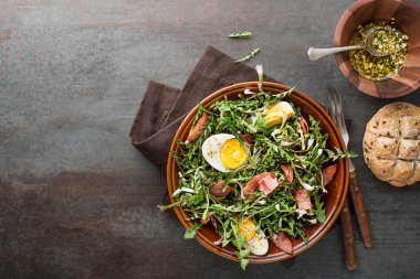 Yumurtalı karahindiba salatası ve gri arka planda pastırma.