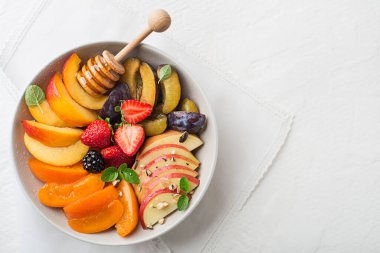 Beyaz arka planda balla tatlandırılmış sağlıklı taze meyve salatası.