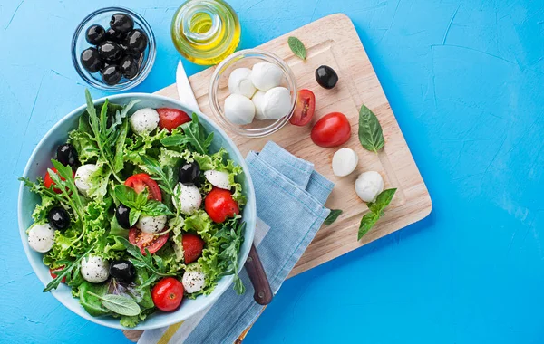 Preparation Green Salad Mozzarella Cheese Black Olives Arugula Tomato Blue —  Fotos de Stock