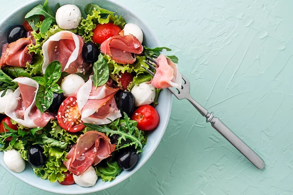 Healthy Green Salad Prosciutto Mozzarella Tomato Olives Green Background Close — Foto de Stock