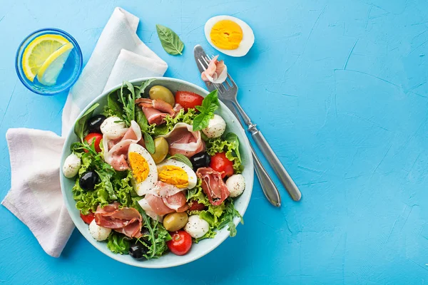 Healthy Green Salad Prosciutto Mozzarella Egg Olives Tomato Blue Table — Stock Photo, Image