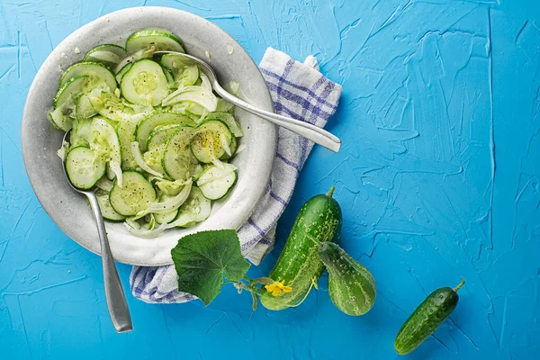 Cucumber salad. Preparation of fresh cucumber salad on blue background