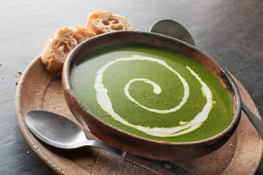 Fresh vegetable creamy soup with cream and on grey background close up.