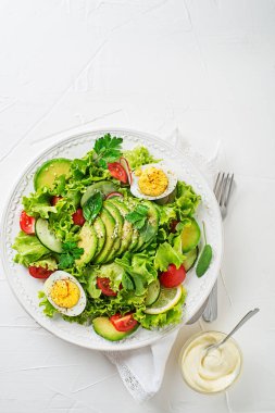 Green mixed salad with avocado, egg and fresh vegetables with creamy dressing 