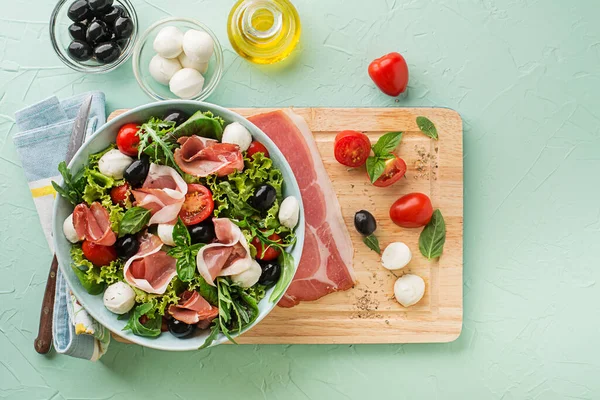 Healthy Green Salad Prosciutto Mozzarella Tomato Olives Green Background — Foto de Stock