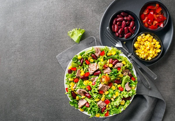 Healthy Green salad with tuna, corn, peppers and beans on grey background. Mexican corn salad.