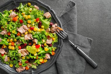Healthy Green salad with tuna and vegetable on grey background close up. Mexican corn salad.