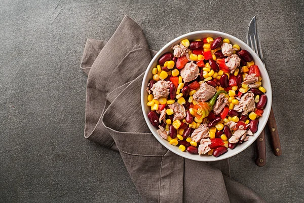 Healthy tuna salad with corn, peppers and beans on grey background. Mexican corn salad.