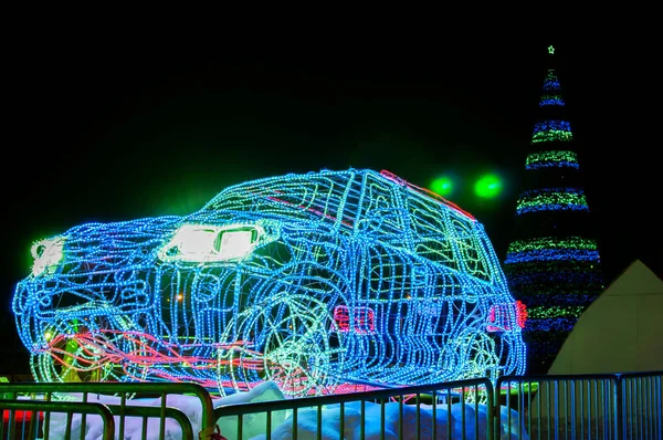 夜城的圣诞树旁 一辆由发光二极管引导的灯泡制成的新年小轿车 — 图库照片
