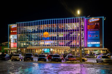 Gece şehrin parlak ışıkları geceleri bir araba ve kış mevsiminde yalnız bir fener için park yerinin yanındaki vitrinlere ışık saçıyor. 
