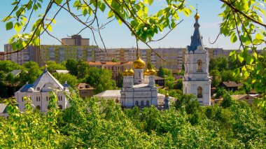 Şehrin arka planında altın kubbeleri ve yeşil yaprakları olan kilise ve tapınak. 